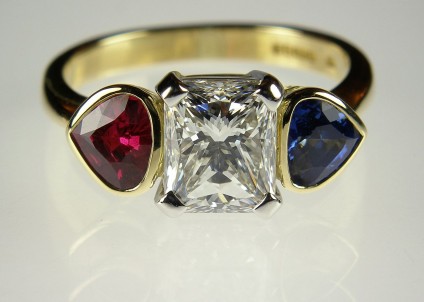 Radiant cut diamond ring with ruby & sapphire flanking stones - 2.03 carat radiant cut diamond H colour VS1 clarity set with fine matching shield cut ruby and sapphire of 60 points each in platinum and 18 carat yellow gold.
