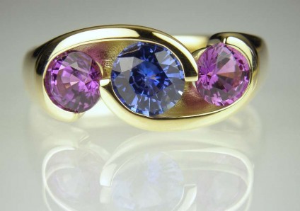 Sapphire ring - 1.33ct round brilliant cut blue sapphire flanked by a matched 1.75ct pair of purple sapphires in 18ct yellow gold