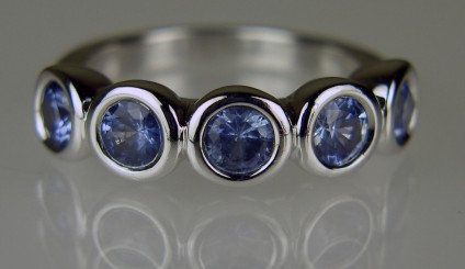 Pastel blue sapphire rubover set five stone ring - Pretty pastel sapphire ring set with five round sapphires totaling 2.65ct in weight, each sapphire is 5mm in diameter, rubover set in 18ct white gold. Ring size P. This ring is secondhand, as is reflected in the modest price. It has been checked, re-polished and re-rhodium plated by Just Gems and comes with our usual 6 month warranty.