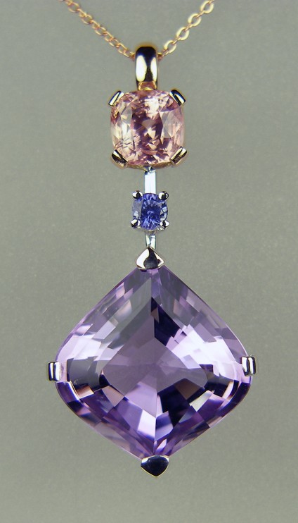 Amethyst & sapphire pendant in rose & white gold - Beautiful onion cut amethyst (cut in Idar Oberstein) set with 0.22ct round natural blue sapphire, both set in 18ct white gold. Also set with a delicate peachy pink 2.85ct cushion cut sapphire mounted in 18ct rose gold. Perfect with either a white or rose gold chain. Pendant measures 40mm long and 20mm wide.

