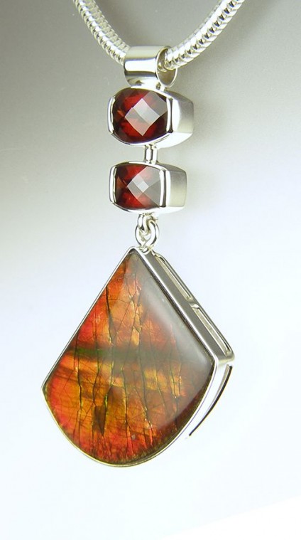Ammolite & garnet pendant in silver - Ammolite & garnet pendant - ammolite (fossilised ammonite shell from Alberta, Canada) set with African pyrope garnet chequerboard cut weighing 1.66 & 2.45ct, mounted as a pendant in silver.
