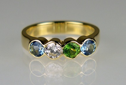Aquamarine, diamond & green garnet birthstone ring - Delicate ring in 18ct yellow gold set with 0.42ct pair of aquamarines, 0.30ct green garnet and 0.23ct diamond in F colour VS clarity. All gems approximately 4mm in diameter. The stones were chosen because the are the birthstones of the parents and children in a family.