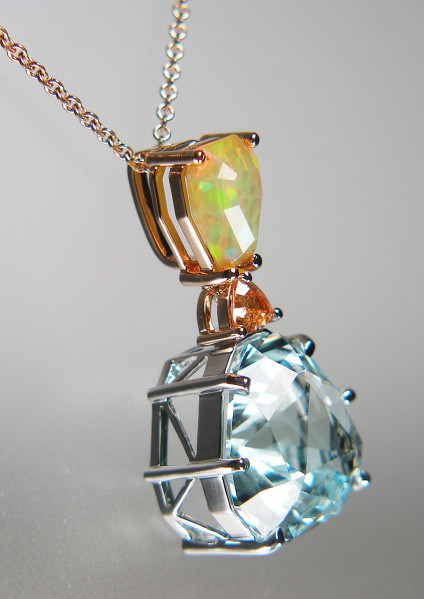 Aquamarine, mandarin garnet & Ethiopian opal pendant in 18ct white & rose gold - Spectacular custom cut aquamarine weighing 17.16ct and 2.23ct drop shaped fected Ethiopian opal, both gems cut by Ivan Williamson of Hascosay Gems, set with a 0.56ct triangular mandarin garnet. The aquamarine is claw set in 18ct white gold, the garnet & opal are set in 18ct rose gold. The pendant is 35mm long. The pendant is suspened from a 16-18" 18ct rose gold chain.