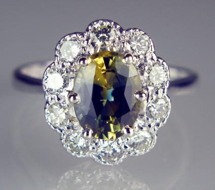 Bi-colour 'Wattle' sapphire & diamond cluster ring in 18ct white gold - Beautiful bi-colour oval cut sapphire from New South Wales, Australia, weighing 2.22ct set with a 0.60ct of white diamonds in 18ct white gold ring.  The sapphire is what is referred to as a 'Wattle' sapphire, named for the yellow flowers and glaucous green leaves of the Australian wattle tree. The stone is actually bi-coloured yellow and blue, the combination of these two colours giving it a lively green flash of colour when the ring is being worn.