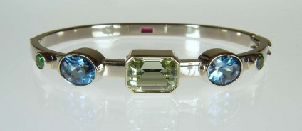 Birthstone bangle - Beautiful bangle made with 5.82ct unheated greenish blue aquamarine emrald cut, 5.78ct pair of oval blue topaz, 0.84ct pair of round brilliant cut green tsavorite garnets and, on the reverse side, a 0.37ct emerald cut Tanzanian ruby. All bezel set in 18ct white gold. 