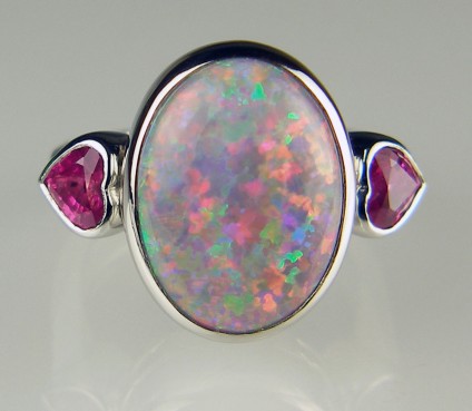 Black opal and pink sapphire heart ring in platinum - 7.73ct oval black solid opal from New South Wales, Australia, set with a 0.93ct pair of bright reddish/pink heart cut sapphires in platinum