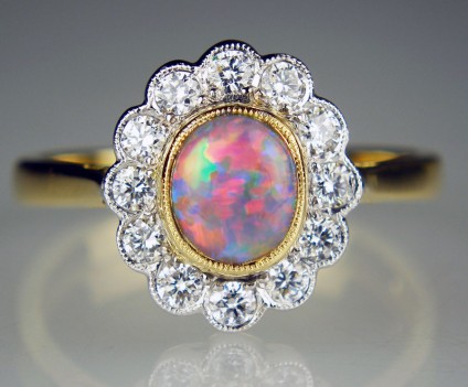 Black opal and diamond halo ring - Beautiful oval cabochon black opal weighing 0.66ct and set with 0.35ct of G colour VS clarity white diamonds in 18ct yellow and white gold ring