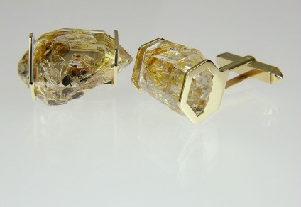 Oil included quartz cufflinks in gold - Cufflinks in 9ct yellow gold, smaller crystals. Rare oil included quartz crystals from Balochistan are set in individually handmade gold mounts.  The crystals are approximately 2-3cm in all dimensions and contain golden droplets of light oil, along with darker bitumen and an aqueous solution.  The inclusions fluoresce a strong bluish green under UV light.  Each pair of cufflinks comes with a UV pen torch and an explanation of the crystal.  These crystals are extremely rare and it is difficult to find such perfect examples as sold by Just Gems.  The setting is precisely made to fit each unique crystal and has to be created without the application of heat, which could cause the crystal to fracture.  Each piece is handmade in Scotland and hallmarked in Edinburgh. Pendants and earrings also available.  A selection of crystals are available for bespoke designs.
