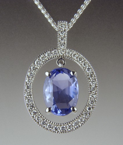Sapphire & Diamond Pendant - Customer's pale blue Sri Llankan sapphire set in diamond set frame pendant in 18ct white gold.  The sapphire moves within the mount to allow maximum sparkle from a shallow stone.  The sapphire was not sourced by Just Gems