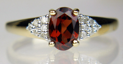 Garnet oval ring with diamond cluster shoulders in 9ct yellow gold - Garnet oval, strong bright red, flanked by a cluster of round brilliant cut diamonds on each shoulder, ring in 9ct yellow gold