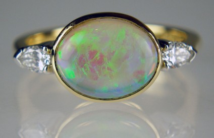 Opal and diamond ring in yellow gold - 1.59ct oval opal cabochon set with 0.21ct pear cut white diamonds in platinum and 18ct yellow gold.