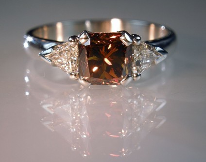 Coloured & white diamond ring in platinum - 1.45ct radiant cut fancy deep orange brown diamond set with 0.41ct trillion cut white diamonds in platinum.
