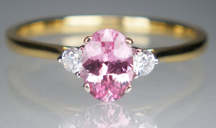 Pink sapphire & diamond ring in 18ct yellow gold - 0.68ct oval natural pink sapphire, claw set and flanked by a 0.11ct pair of round brilliant cut diamonds in G colour VS clarity, all mounted in 18ct white gold on an 18ct yellow gold shank