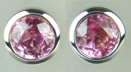 Pink sapphire earstuds in 9ct white gold - 5.1mm round pink sapphire earstuds in rubover white gold setting. The pair of pink sapphire rounds weigh 0.60ct.