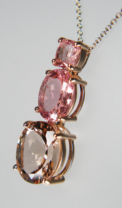 Morganite, tourmaline & spinel pendant in 9ct rose gold - Subtle shades of pink gems in this enchanting pendant in 9ct rose gold. Set with a 1.43ct cushion cut pink spinel from Burma, an oval 3.7ct pink tourmaline and a 6.61ct oval morganite. All gems are claw set. The chain runs behind the pendant. The pendant is 33mm long.