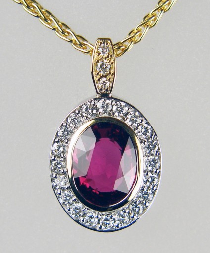 Ruby & diamond pendant - Pendant in 18ct yellow and white gold, set with a central 2.18ct oval faceted natural unheated ruby accompanied by GRS report GRS2015-037034 dated 6th March 2015. 

The ruby is surrounded by a halo of 20 pavé set 1.5mm round brilliant cut diamonds in F colour VS clarity. The pendant is suspended from a bail set with a single 1.5mm round diamond and 2 x 1.2mm round diamonds of the same quality.  Total diamond weight 0.28ct.

The pendant is suspended from an 18ct yellow gold chain 16-19” adjustable.
