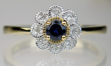Sapphire & diamond cluster ring in 9ct yellow gold - Little flower-like ring set with a dark sapphire round cut surrounded by a halo of tiny round brilliant cut with diamonds, in 9ct yellow gold