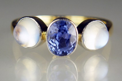 Sapphire & moonstone ring in yellow gold & platinum - Antique ring in 14ct yellow gold and platinum, set with a central oval faceted unheated natural sapphire in a pretty harebell blue and flanked by a matched pair of round cabochon moonstones. We estimate the sapphire to weigh approximately 1.5ct  (7.5 x 5.7 mm) and the moonstones almost 1ct each stone (6mm rounds). The stones are rubover set with a thin veneer of platinum to minimise visibility of the mount.  This is a very beautiful and unusual ring , finger size Q.