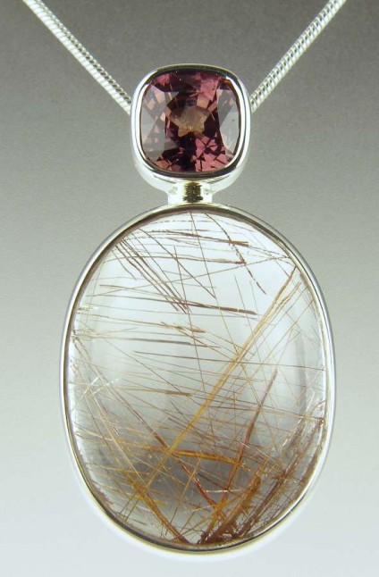 Rutilated quartz & brown sapphire pendant - 14.92ct oval cabochon of rutile included quartz (also know as Venus hair stone) set with a 1.5ct pinkish brown cushion cut sapphire as a pendant mounted in silver