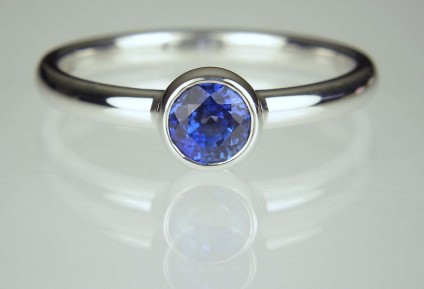 Sapphire Ring - 0.69ct round brilliant cut rich blue sapphire ring in delicate rubover setting in 18ct white gold