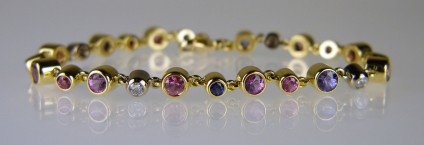 Sapphire & diamond bracelet in lilacs,blues and pinks - Lady’s bracelet in 18ct yellow and white gold, set with 3.72ct of 4mm round sapphires in shades of lilac and pink; 0.45ct of 3mm round pink sapphires; 0.58ct of 3mm round blue sapphires and 0.45ct of 3mm round diamonds in F colour VS clarity. The sapphires are rubover set in yellow gold and the diamond rubover set in white gold.