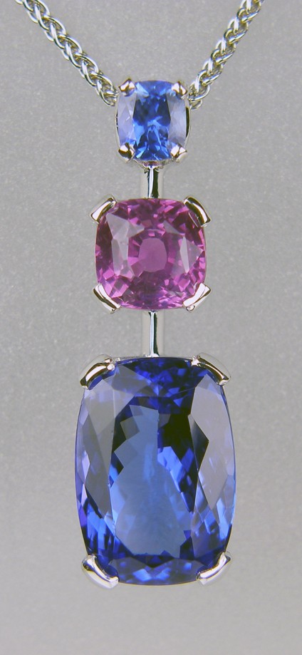Tanzanite & sapphire pendant in 18ct white gold - 0.46ct rectangular cushion cut natural blue sapphire, set with 2.02ct square cushion cut natural vivid pink sapphire and 6.05ct rectangular cushion cut tanzanite, all set in 18ct white gold. The pendant is 29mm long and 9mm wide.

