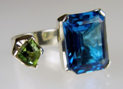 Tourmaline & blue topaz ring in silver - Between the finger ring made with customer's own 26.57ct emerald cut blue topaz and Just Gems shield cut green tourmaline, in silver. 